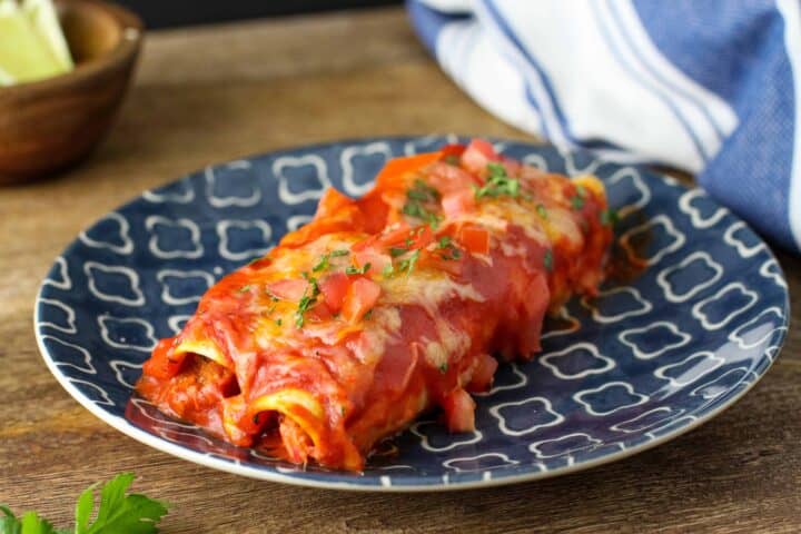 A plate of chicken enchiladas with red sauce. 