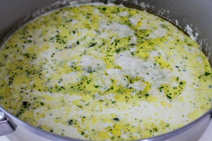 Alfredo sauce shown in a sauce pan after melting the butter and adding in the cream.