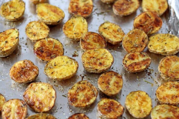 Close up image of crispy golden brown roasted potatoes with herbs.