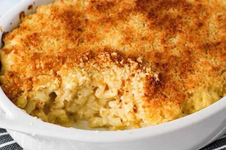 Baked mac and cheese in a dish with a serving scooped out. 