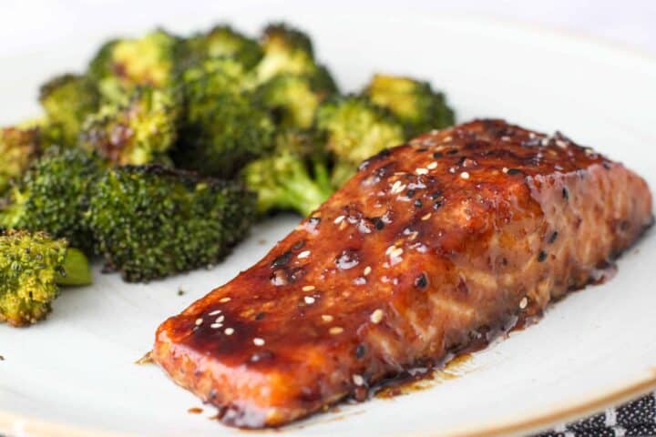 Glazed salmon on a plate with a serving of roasted broccoli.