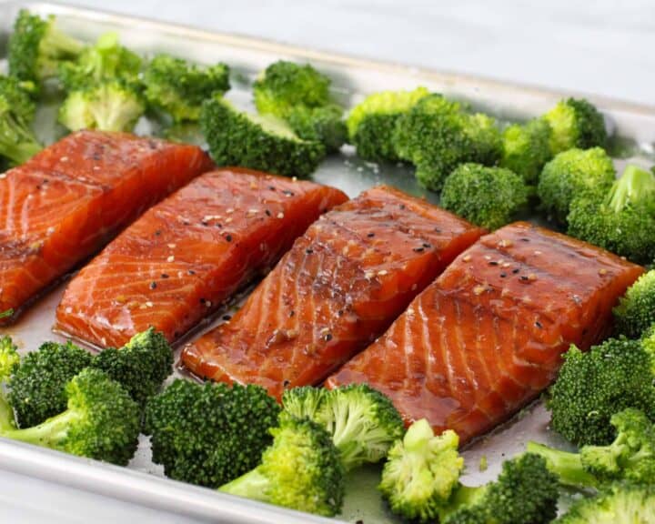 Marinated Soy Ginger Salmon on a sheet pan surrounded by broccoli prior to baking.