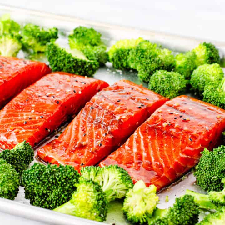 Marinated Soy Ginger Salmon on a sheet pan surrounded by broccoli prior to baking.
