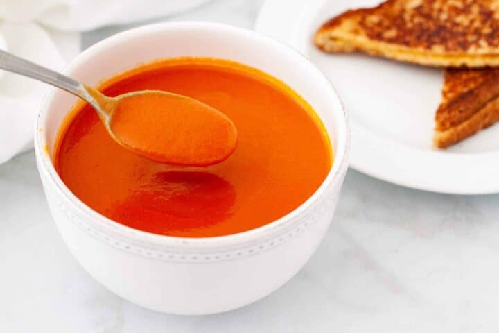 Hot bowl of tomato soup served with a grilled cheese sandwich.