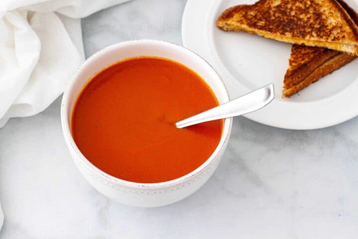 Hot bowl of tomato soup served with a grilled cheese sandwich.