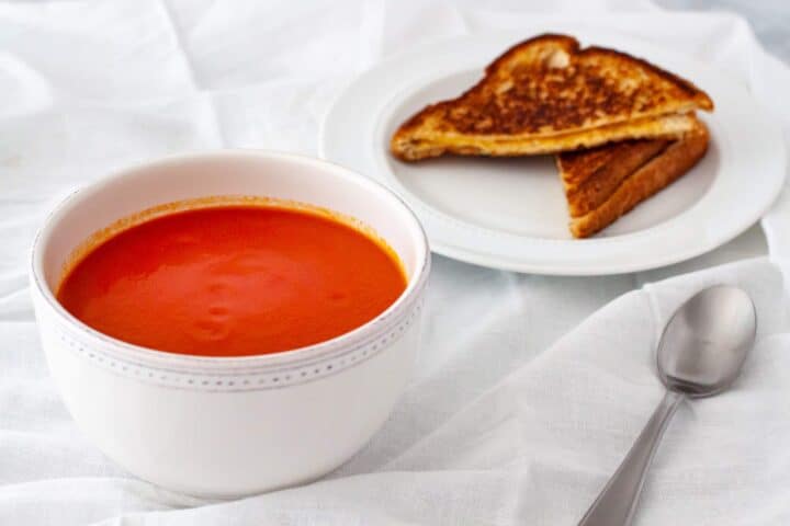 Hot bowl of tomato soup served with a grilled cheese sandwich.