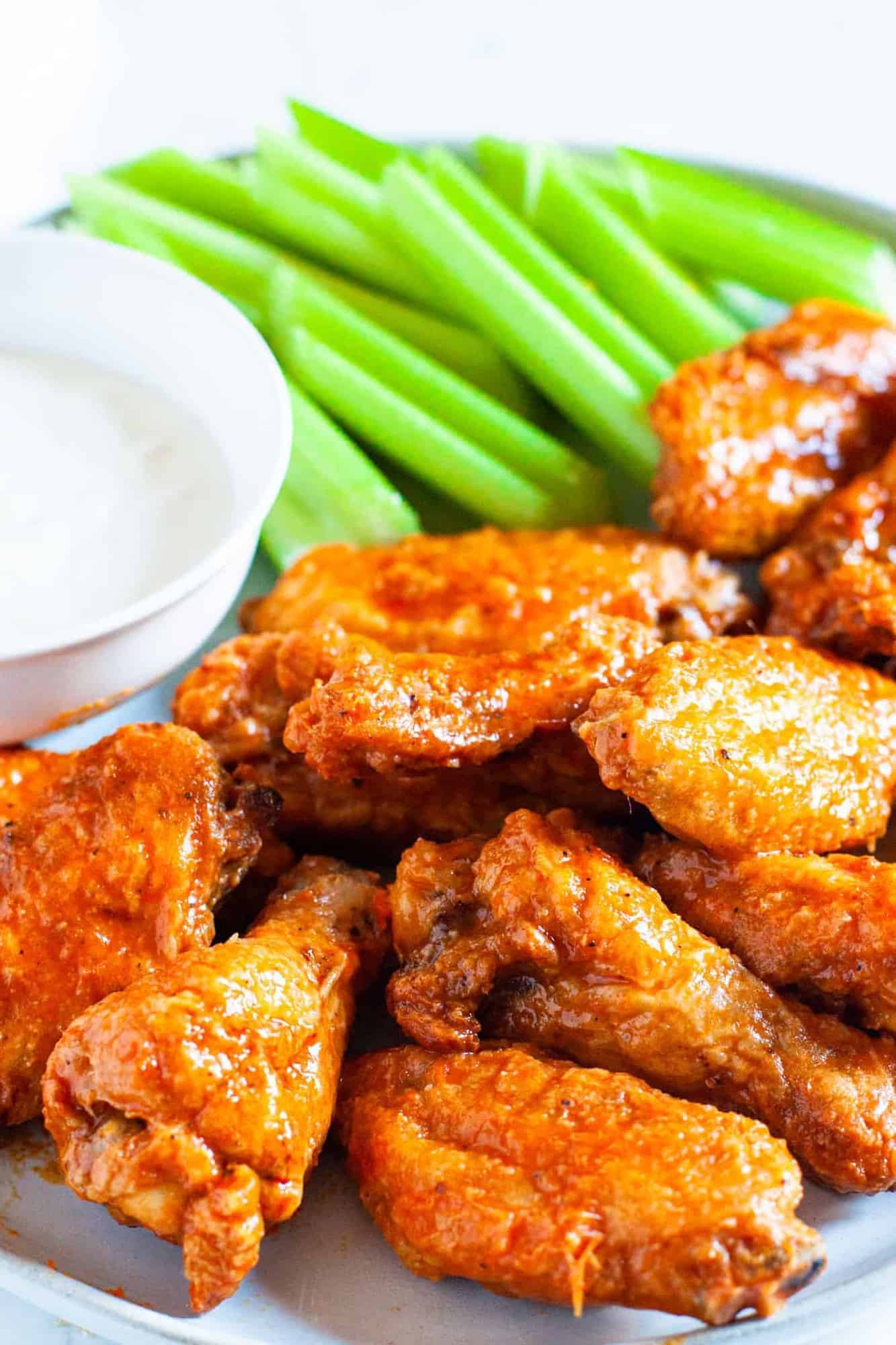 Oven baked buffalo wings shown served on a platter with celery and dipping sauce.