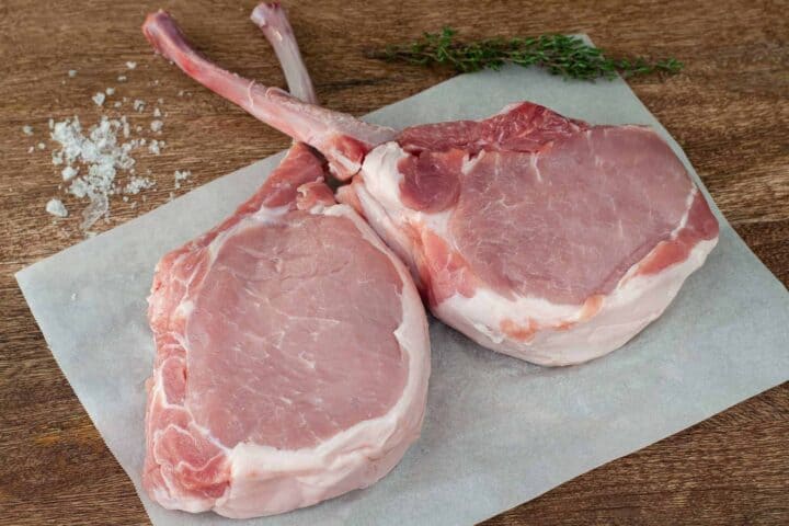 Pork chops shown set on a cutting board prior to cooking.