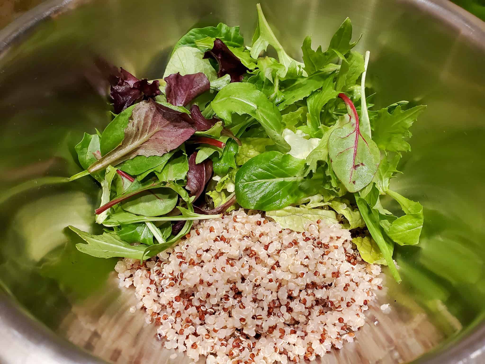 Quinoa and salad greens shown in a mixing bowl.