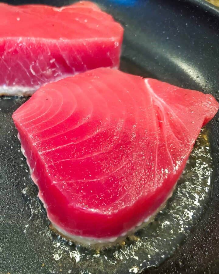 Tuna shown cooking in a hot pan.