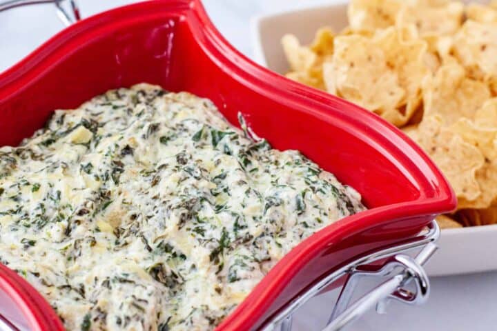 Spinach Artichoke Dip served in a baking dish with tortilla chips.