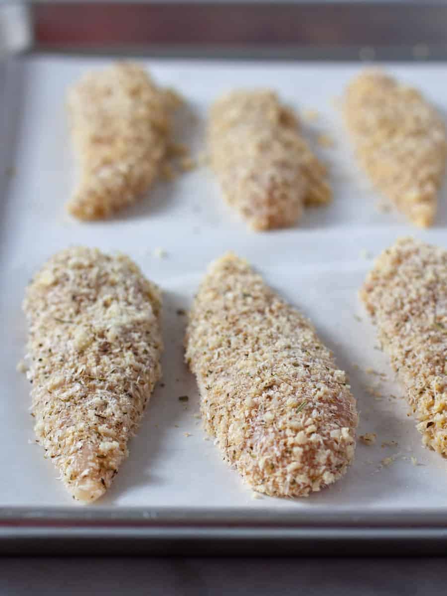 Panko breaded chicken tenders on sheet pan before cooking.