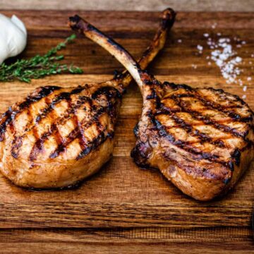 Grilled pork chops shown on a wood cutting board.