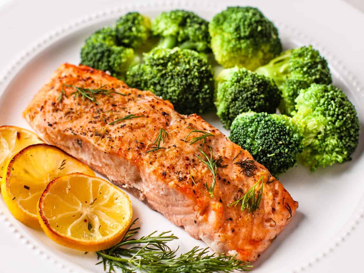 The finished lemon dill salmon served on plate with a side of steamed broccoli.