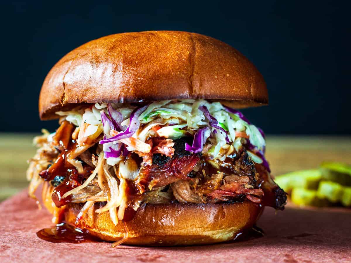 Pulled pork sandwich topped with slaw and bbq sauce.