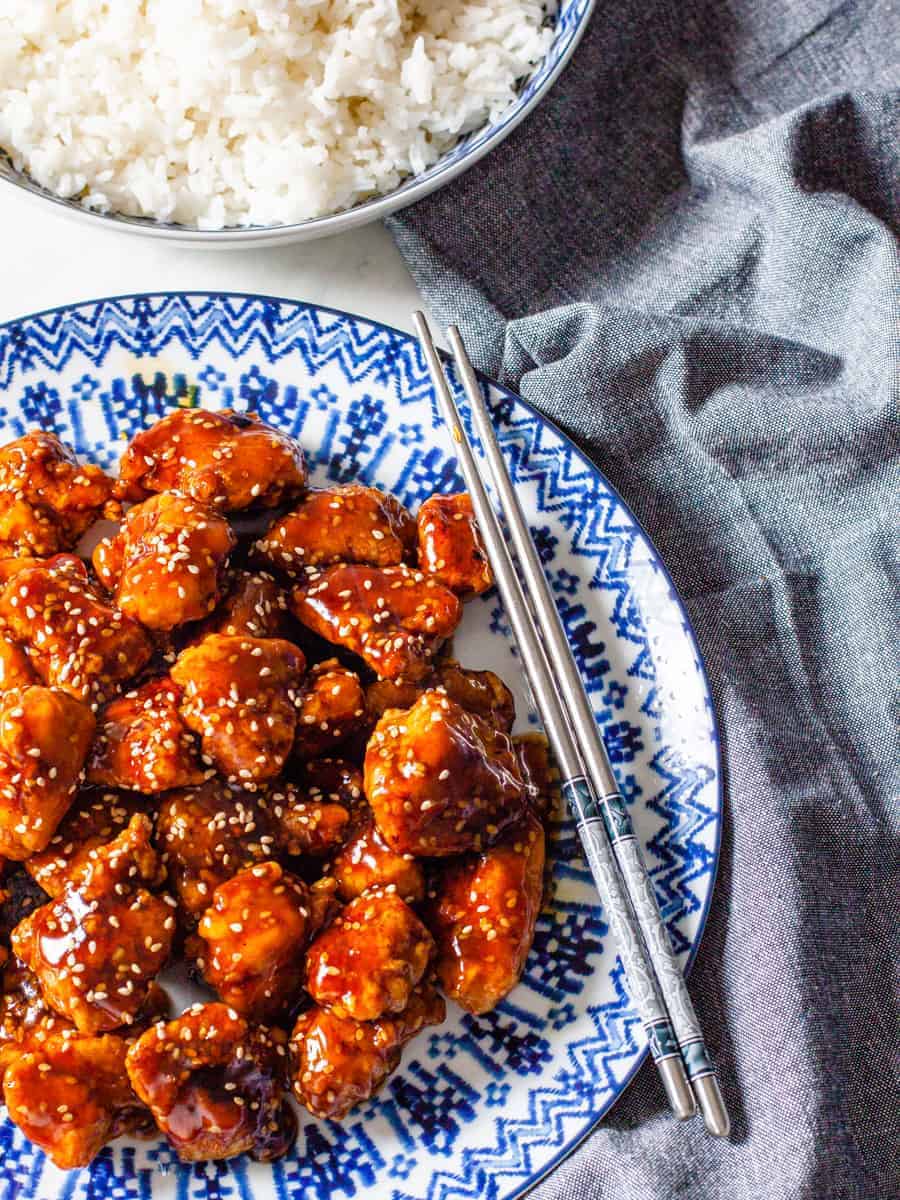 Sesame chicken served on a platter with a side of steamed rice.