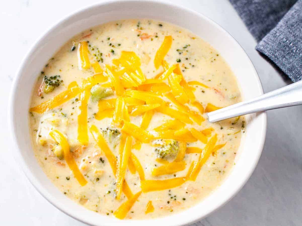 Overhead image of a large bowl of creamy broccoli cheese soup topped with grated cheddar cheese.