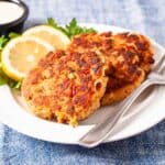 Golden brown salmon cakes served on a plate with fresh sliced lemon and dipping sauce