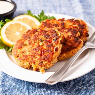 Golden brown salmon cakes served on a plate with fresh sliced lemon and dipping sauce