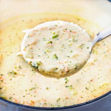 Ladle of creamy broccoli cheese soup being scooped from the pot.