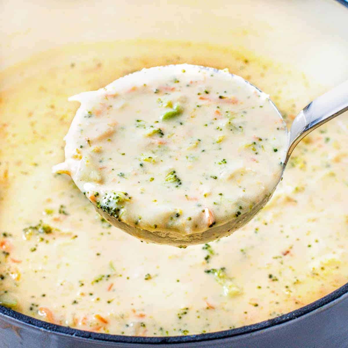 Ladle of creamy broccoli cheese soup being scooped from the pot.