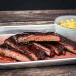 A platter of sliced ribs served with mac and cheese.