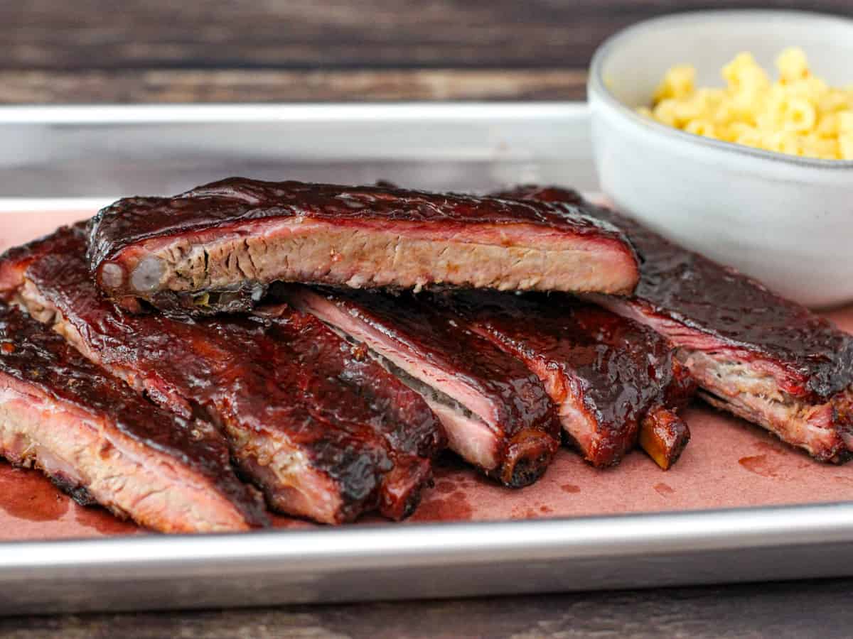 Finished smoked pork spare ribs coated with bbq sauce and served on a platter.