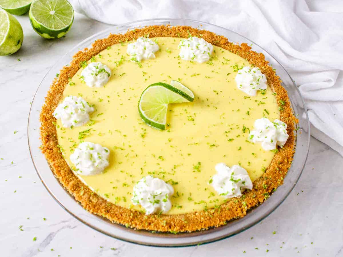 A whole key lime pie, topped with whipped cream, lime zest, and a lime twist.