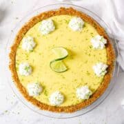 Close up overhead shot of finished key lime pie, topped with whipped cream, lime zest , and a lime twist.