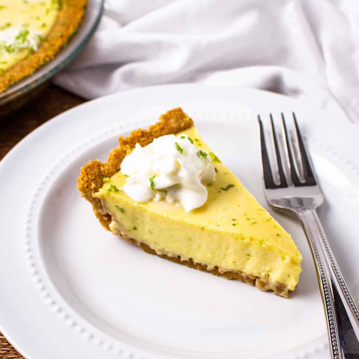 A slice of key lime pie served with whipped cream.