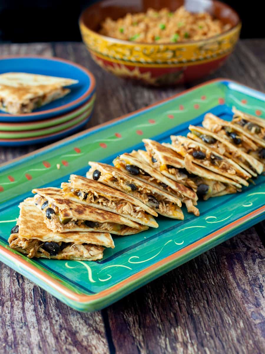Chicken and black bean quesadillas shown sliced into wedges and served on a platter.