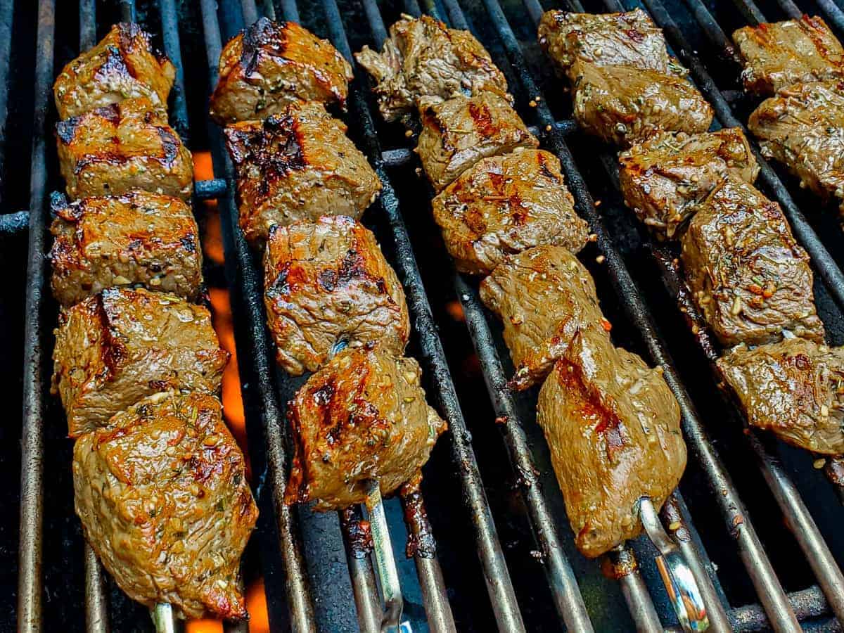 Steak kabobs cooking on a hot grill.