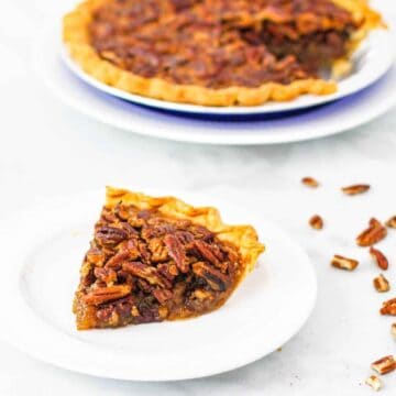 Side angle view of a large slice of pecan pie beside a whole pecan pie.