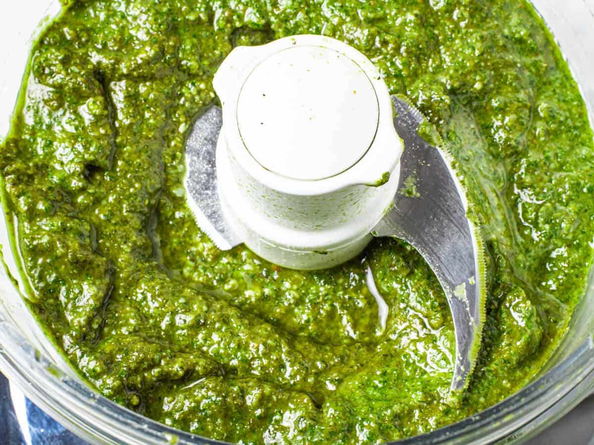 Close up image of the finished pesto sauce in a food processor.