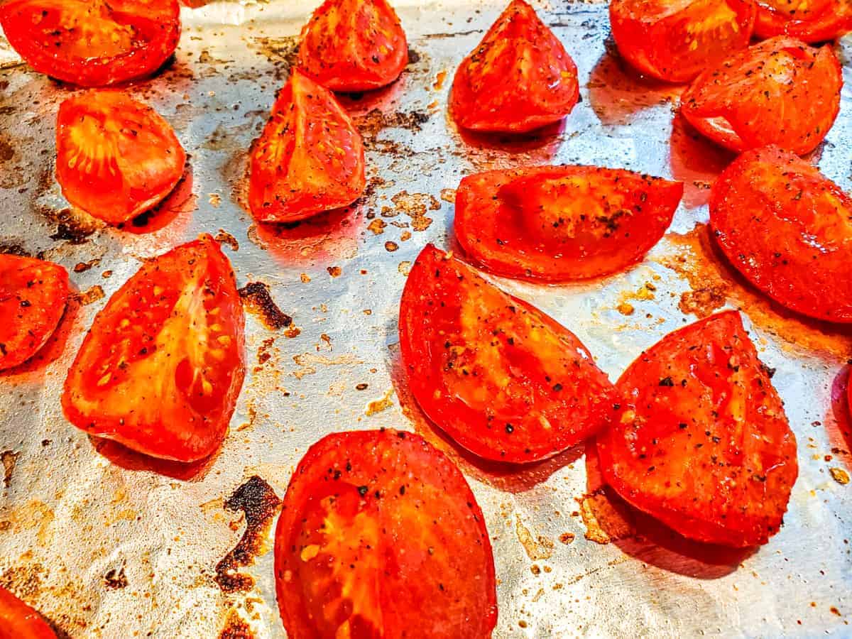 Close up view of oven roasted tomatoes on a baking sheet. 