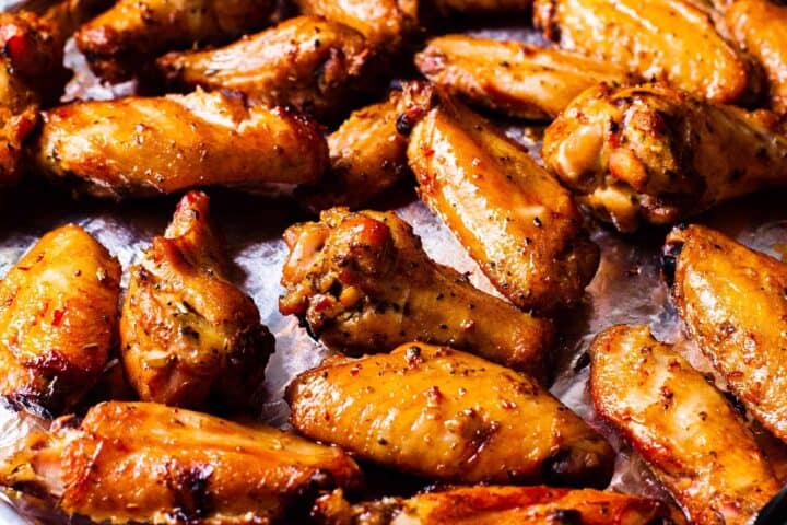 Side view of a rimmed baking sheets filled with golden brown smoked chicken wings.