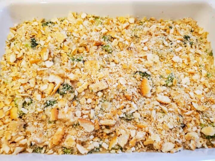 The chicken casserole is shown topped with crumbled crackers before baking.