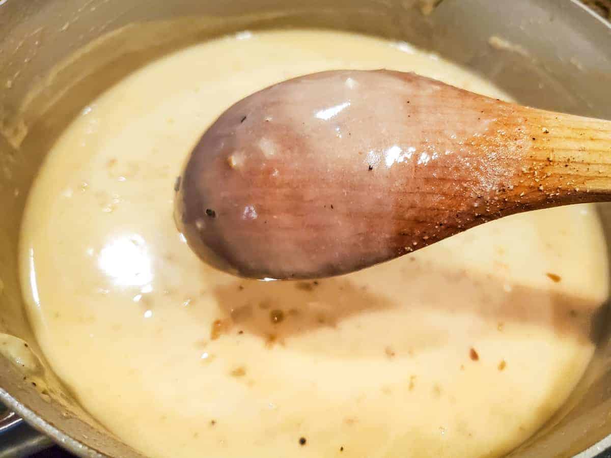 The creamy sauce is shown cooking in a saucepan.