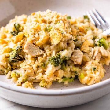 Side angle view of a serving of cheesy chicken and rice casserole with broccoli.