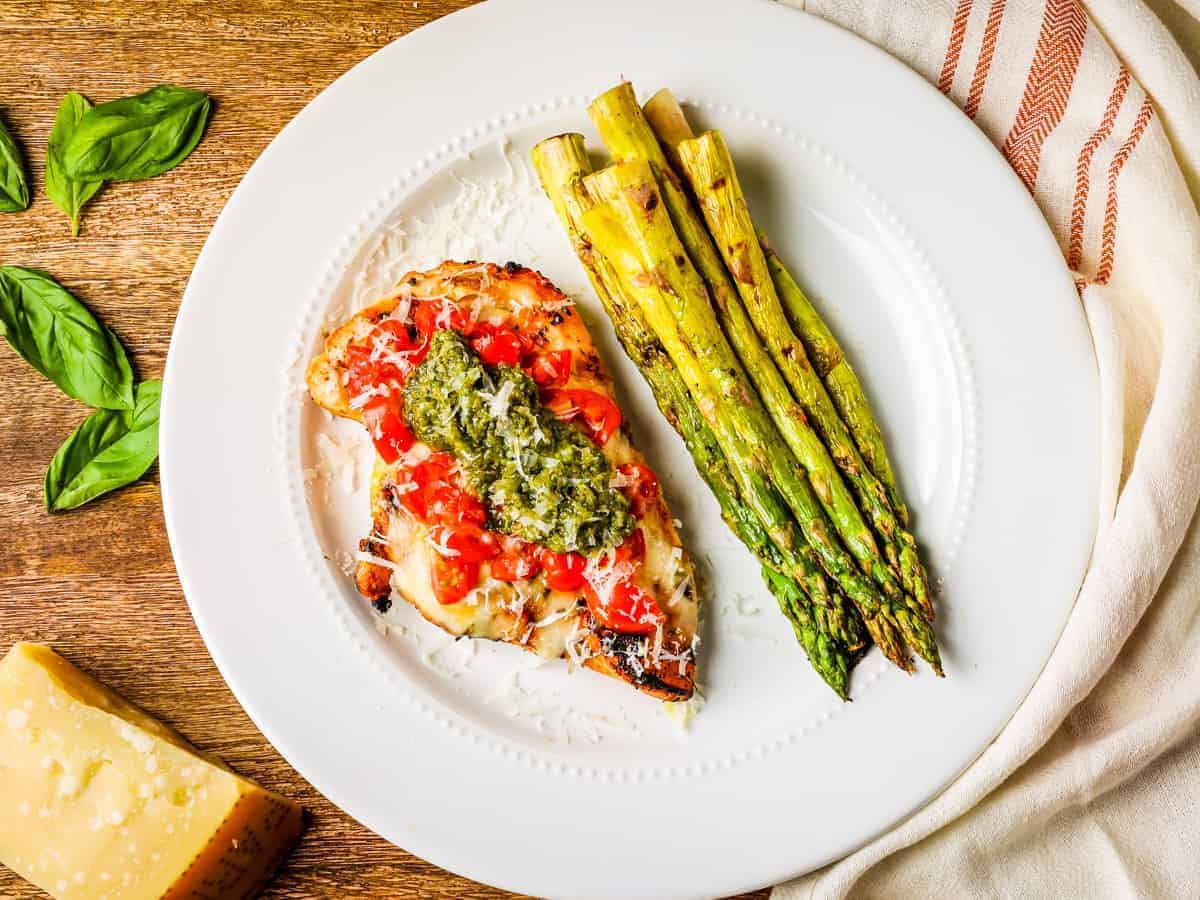 Overhead image of a plate of grilled chicken caprese served with grilled asparagus.