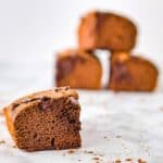A single chocolate pumpkin swirl brownie is set on a counter with a stack of brownies blurred in the background.