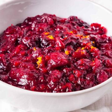 Homemade cranberry sauce served in a white bowl and topped with orange zest.