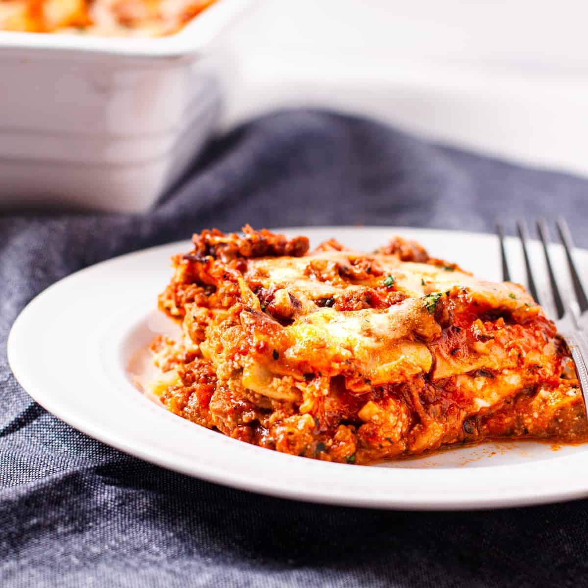 Close up view of a slice of homemade lasagna showing the layers of meat sauce, cheese, and noodles.