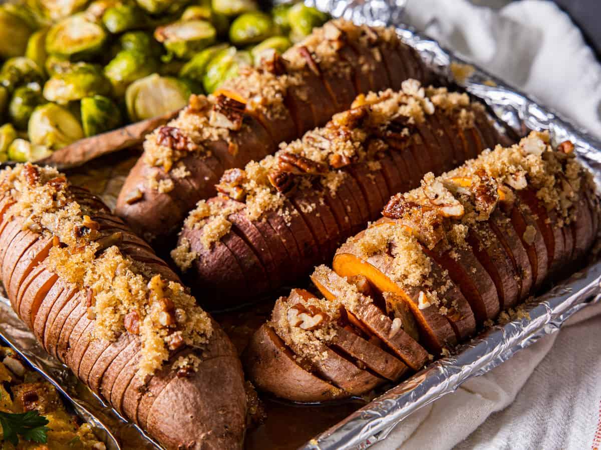 Close up view of the hasselback sweet potatoes topped with brown sugar and pecans.