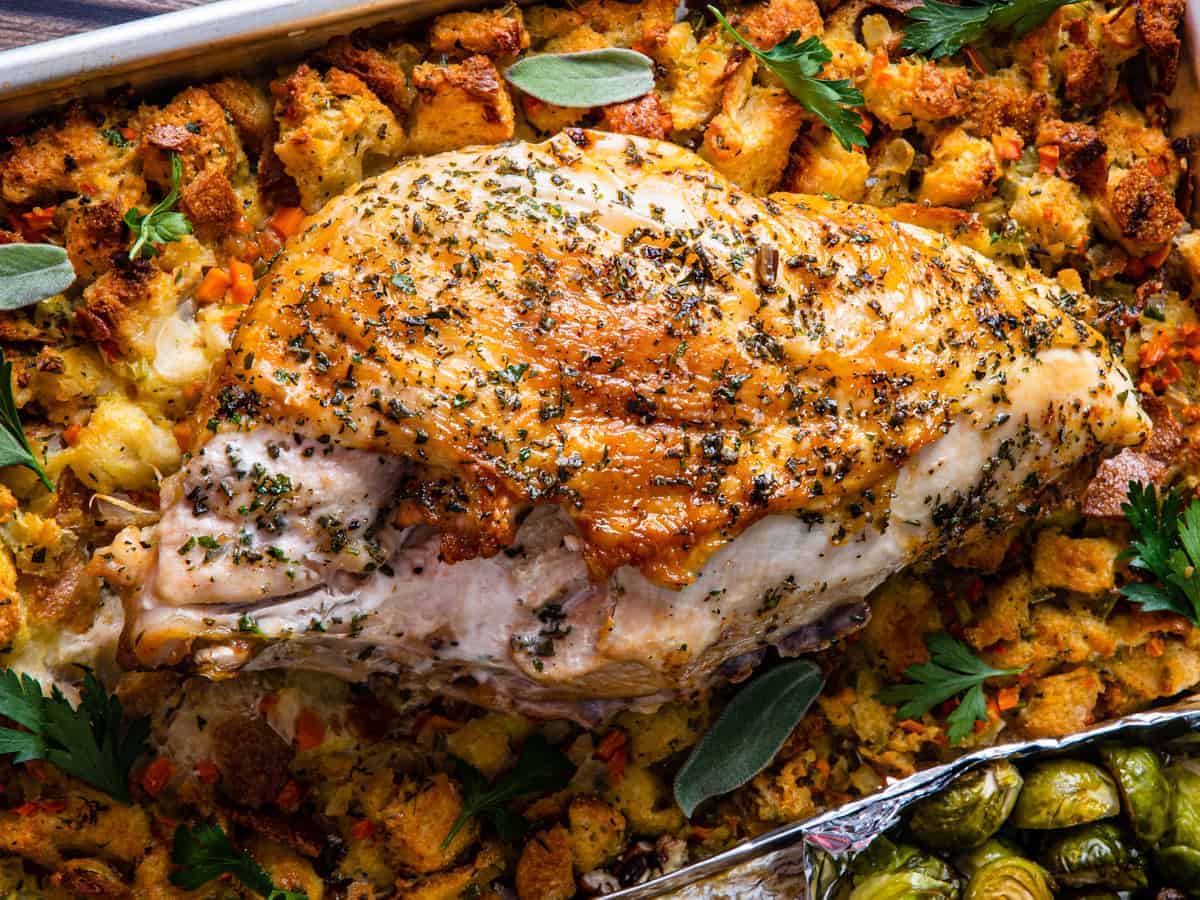 A close up shot of the herb roasted turkey breast set on top of the stuffing.