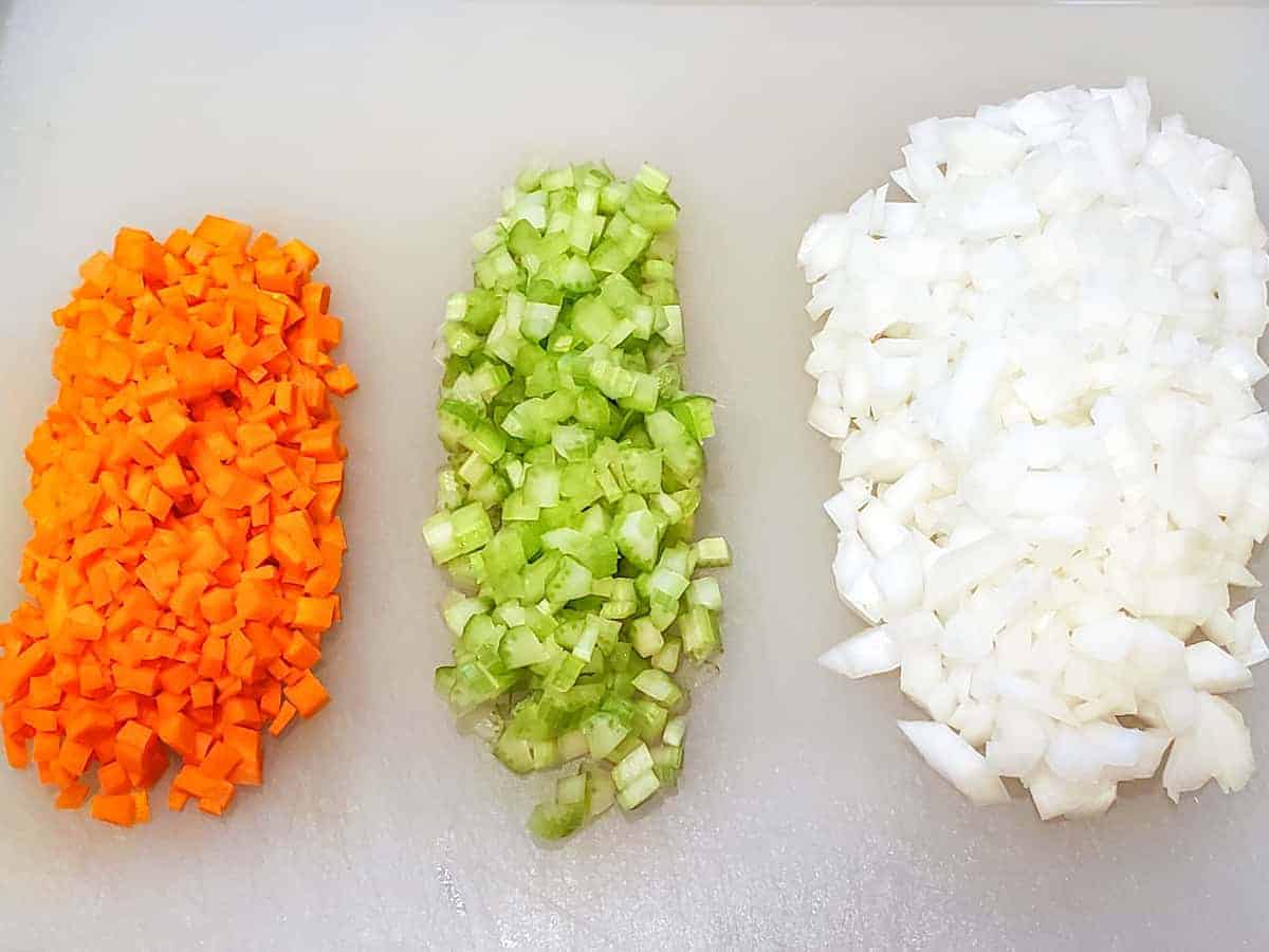 Diced carrots, celery, and onion shown on a cutting board