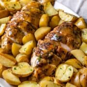 Skillet roasted chicken with potatoes shown in a cast iron skillet topped with a pan sauce.