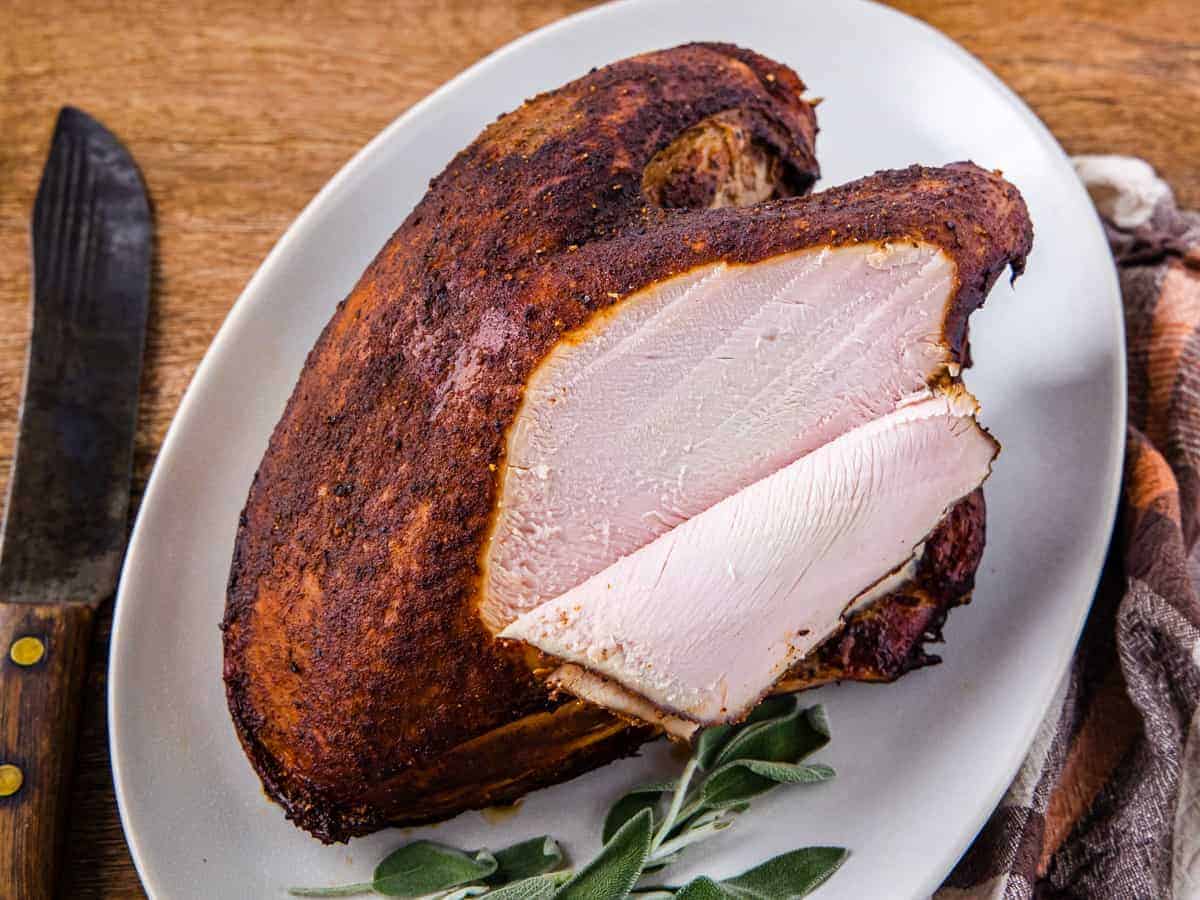 Smoked turkey breast with slices removed from one side.