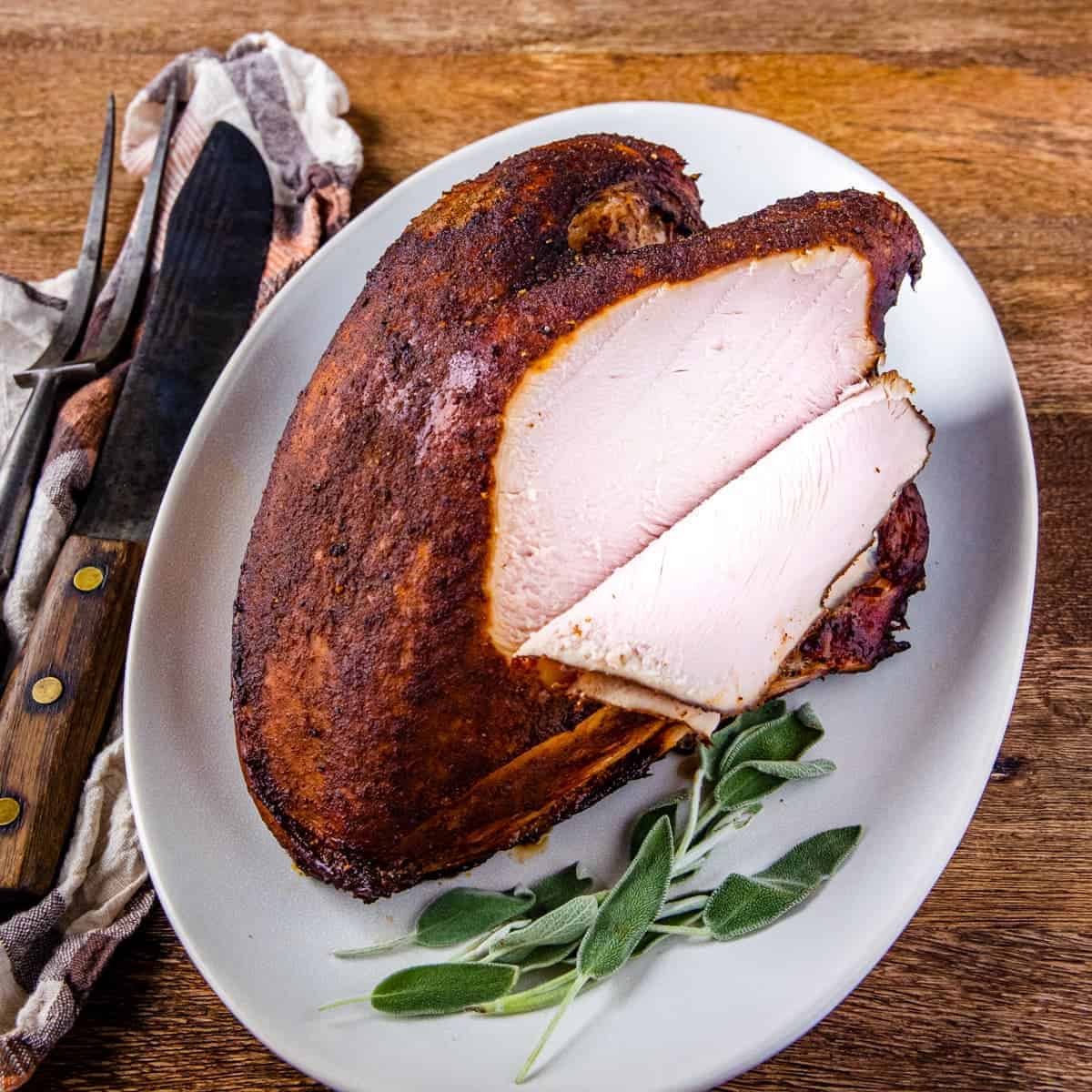 Smoked turkey breast shown on a serving platter with pieces sliced off.