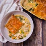 Overhead view of a plate of turkey pot pie se beside a baking dish of pot pie.